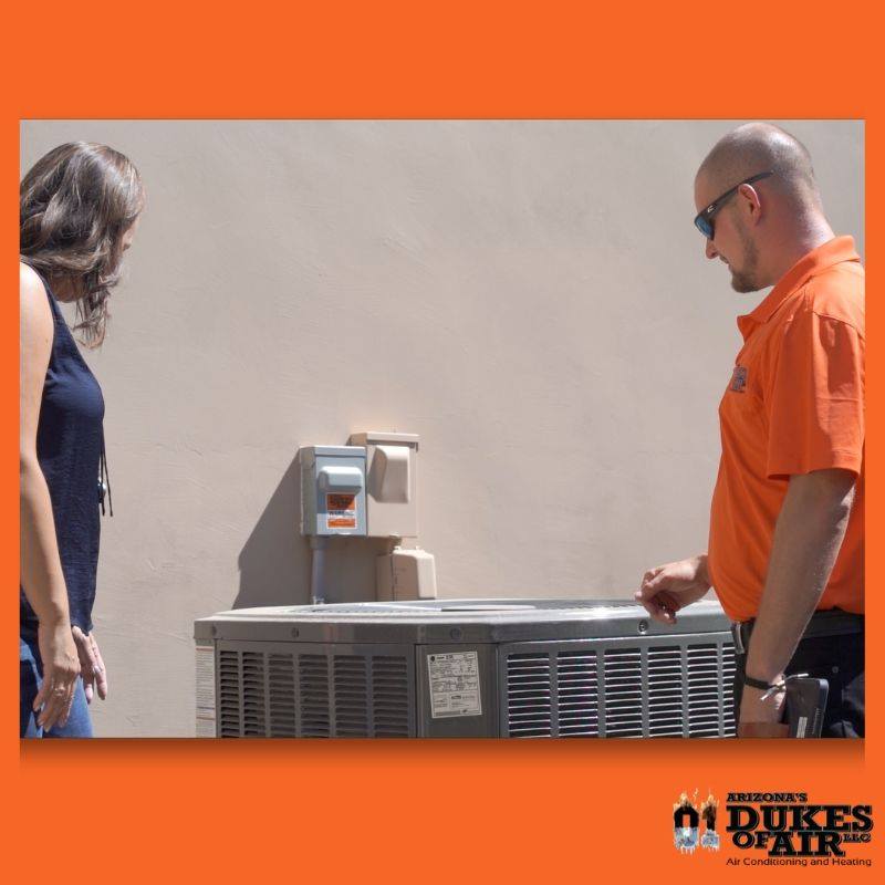 dukes of air employee evaluating hvac system outside with client